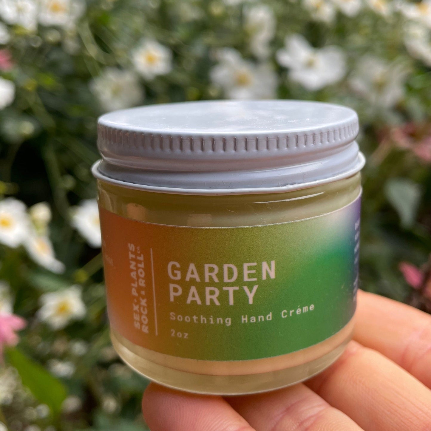 2 oz jar displayed on a hand with a background of flowers